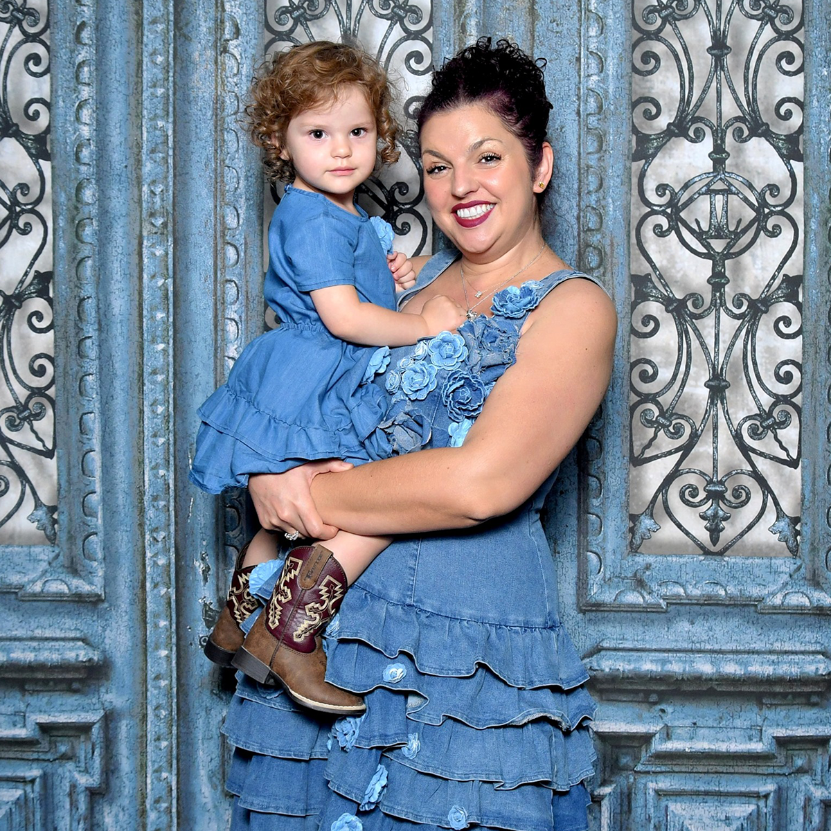 Dr. Adelina Petrova, DMD smiling while holding young girl in blue dress